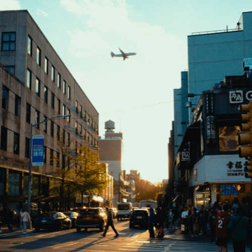 Plane flying over busy street.