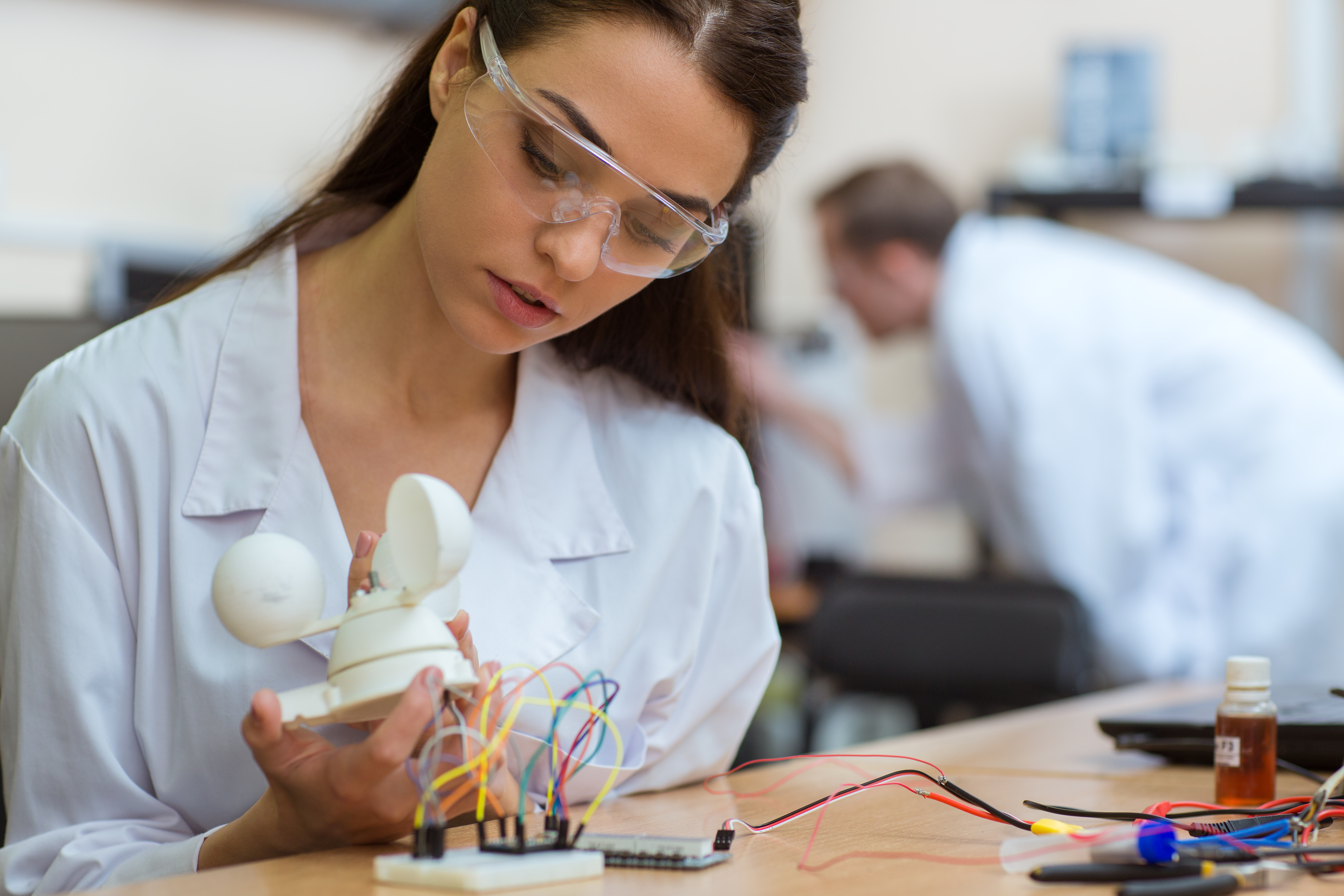 Close up of female engineer with serious facial expression checking detail of mechanical robot.
