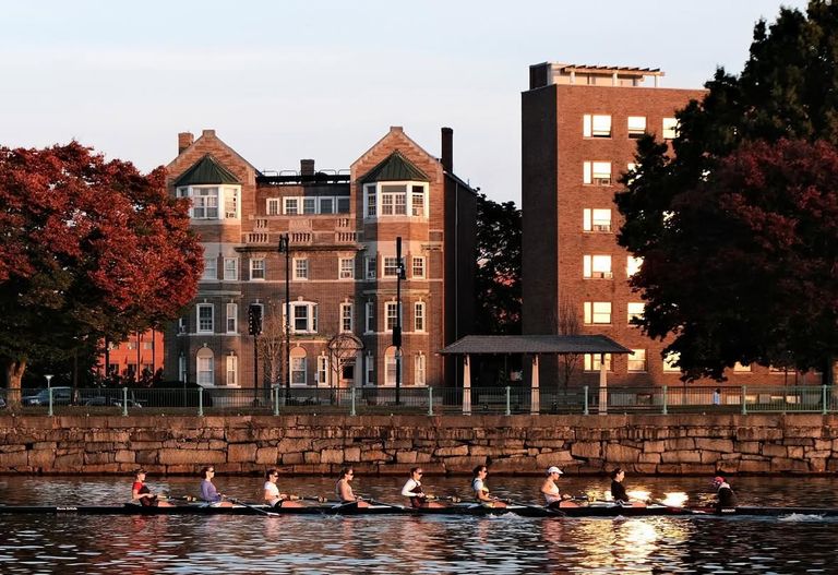 women rowing on an 8 person crew boat on the charles river looking towards cambridge