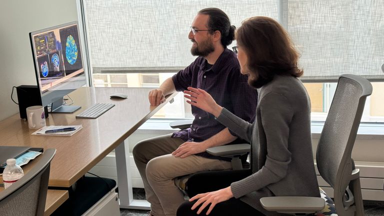Two people seated at a computer monitor