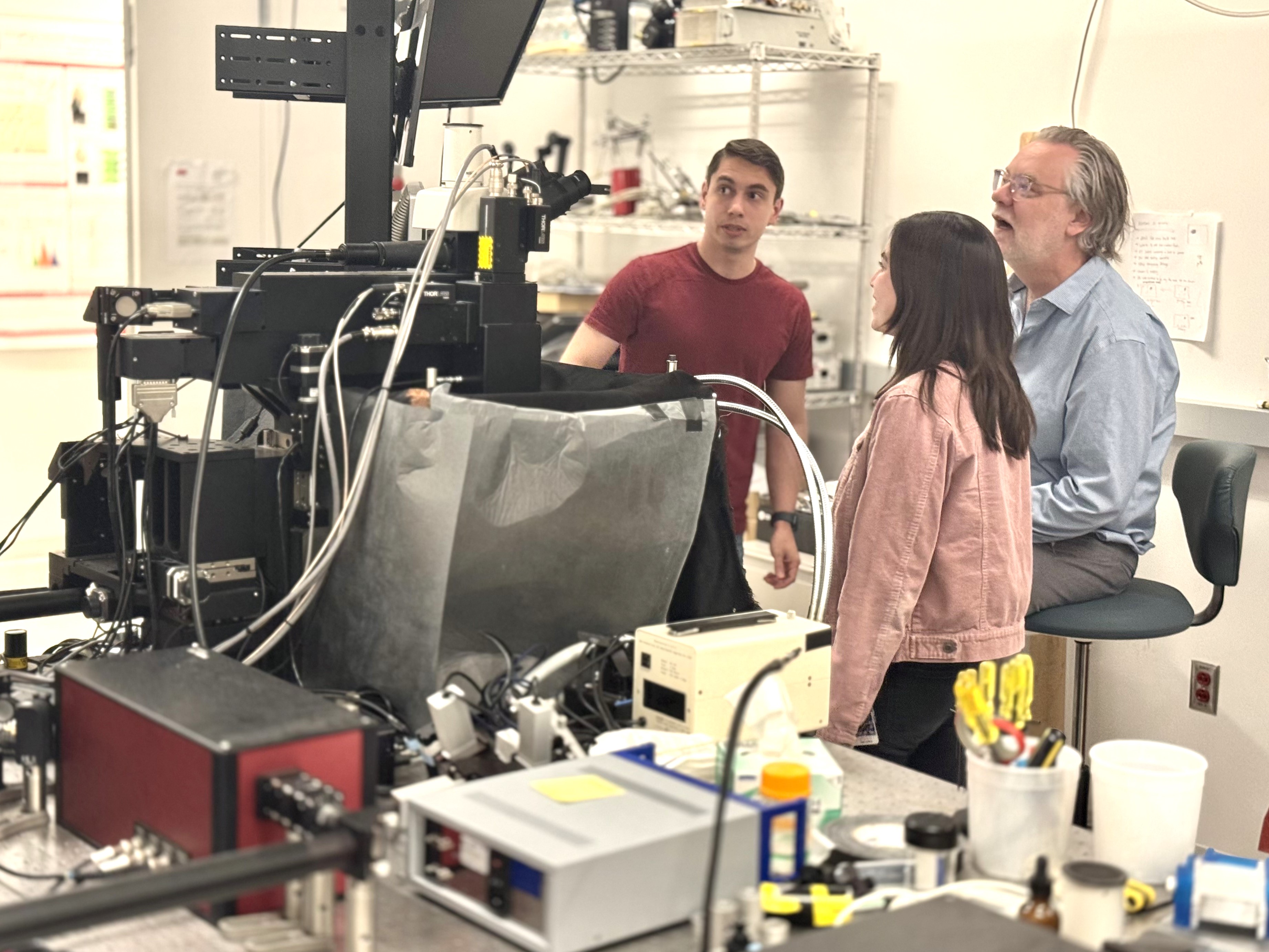three people in a lab looking at a monitor