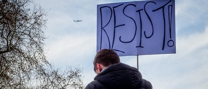 Protester holding a sign that says "Resist!"