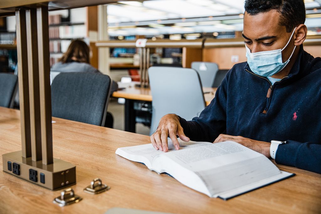 Students study in the library wearing masks