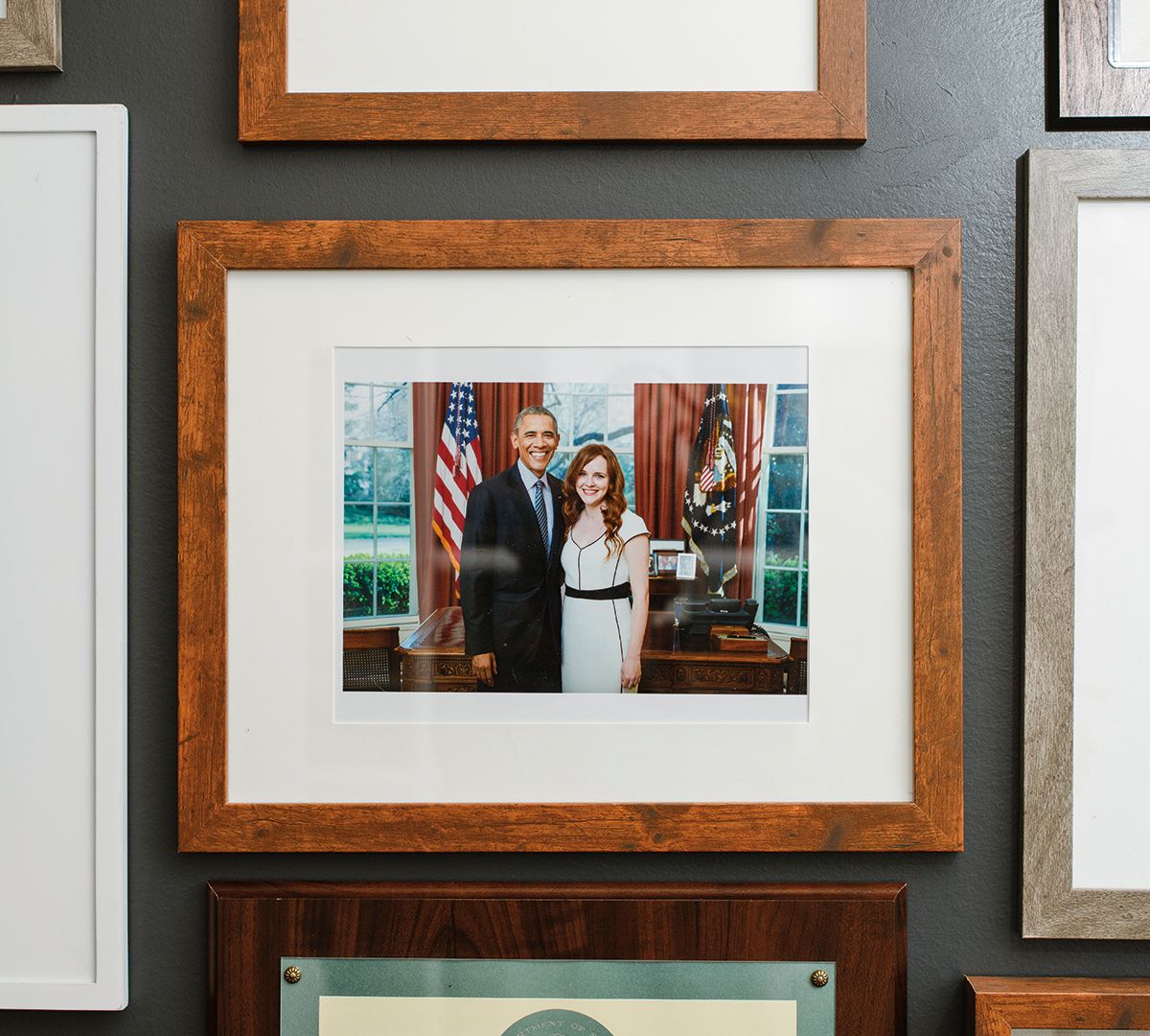 A photo of Leanne Erdberg Steadman's ('08) gallery wall. The frame directly in focus shows Erdberg Steadman with President Obama