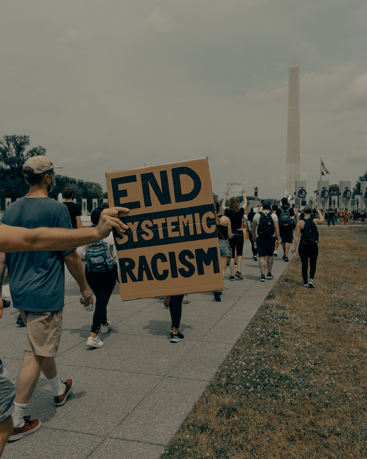 A protest sign reads "End Systemic Racism"