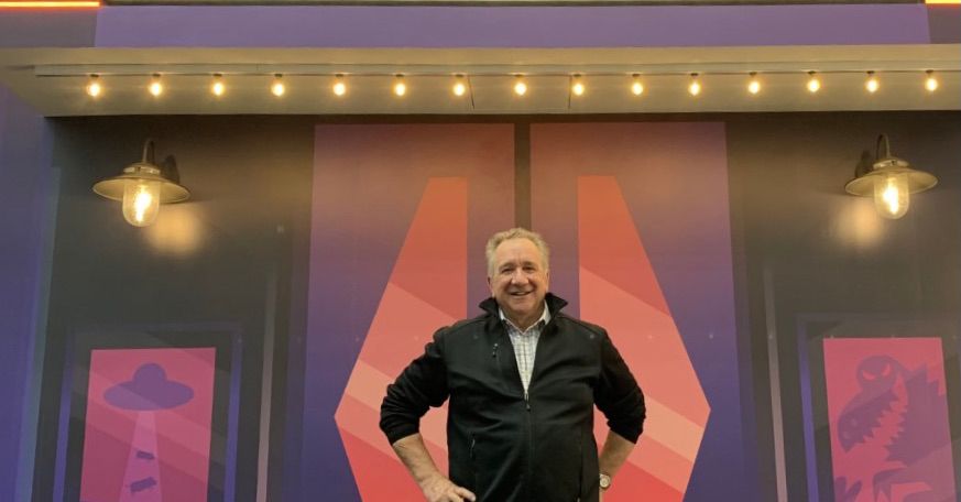 Steve Kay stands in front of the Roku headquarters, with a theater marquee that reads "Welcome."