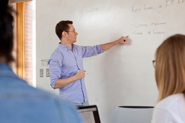 Lecturer Sam Taylor stands at a whiteboard teaching students the Startup Law Clinic