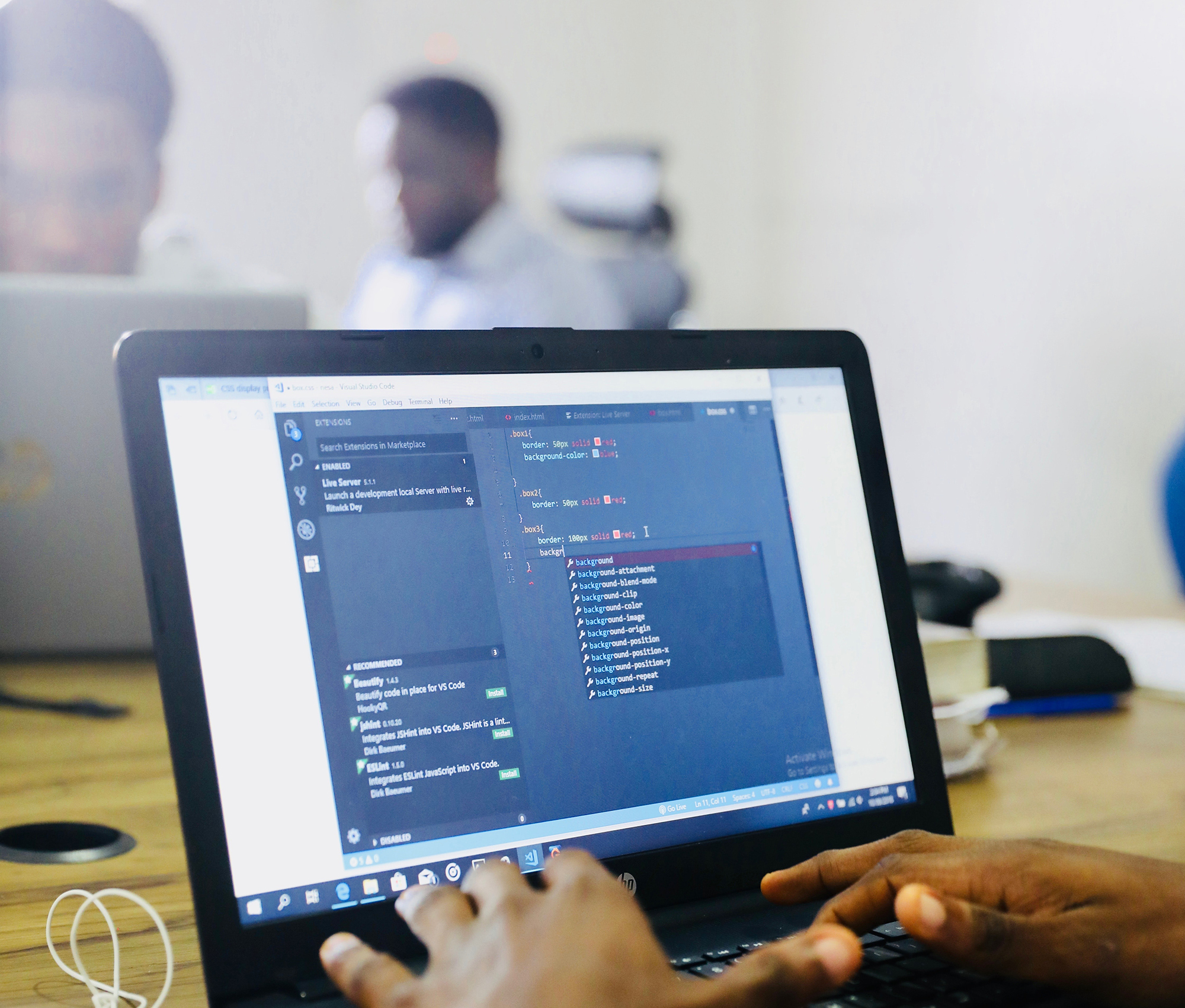 A Black man sits at a computer, coding