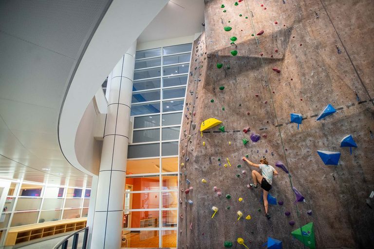 student scaling indoor rock climbing wall at BU's gym