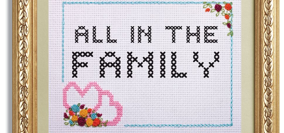 A framed cross stitch of the words "All in the Family"