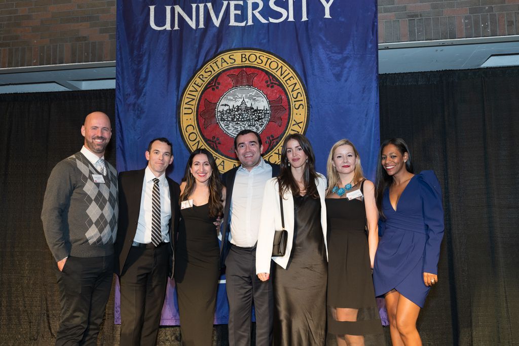Alumni gather for a group photo in front of the Boston University logo.