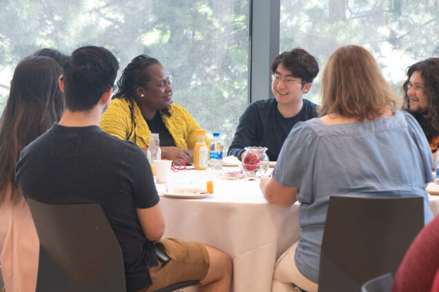 Dean Angela Onwuachi-Willig sits at a table with participants in the 2022 Summer PreLaw Academy at BU Law
