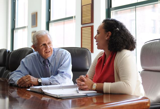 A student discusses a case with a practicing lawyer in a board room.