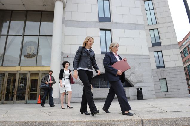 Four people in business attire walk outside of a courthouse in Massachusetts.