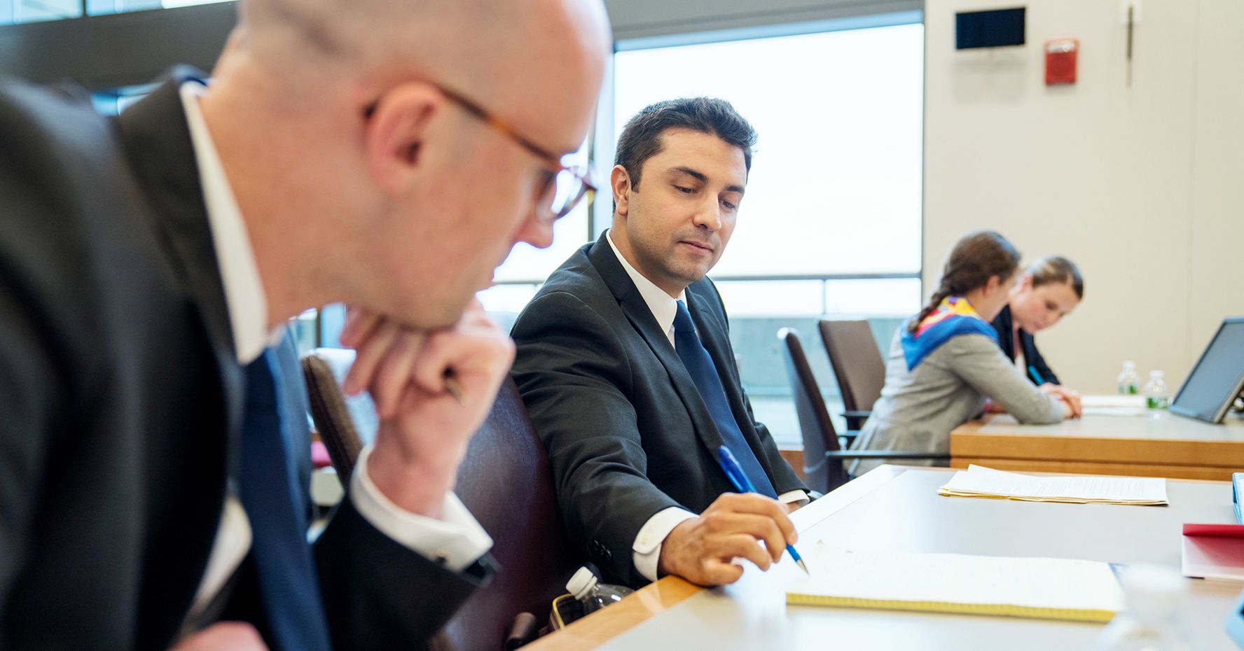 Two men review a document in the courtroom at BU Law.