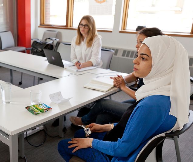 Students sit around a large conference table.