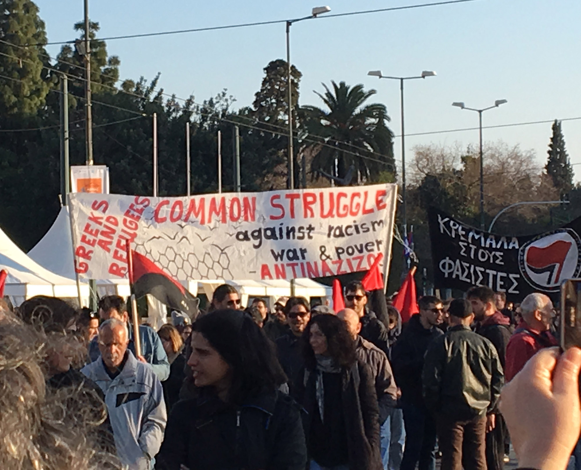 People march carrying a banner that reads, "Greeks and refugees common struggle against racism, war and poverty."