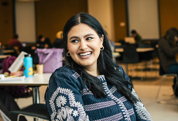 A student smiles and looks over her shoulder in the law school cafe.