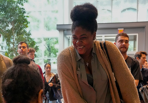 A standing woman smiles as she speaks with a seated person at an event in the law tower atrium.