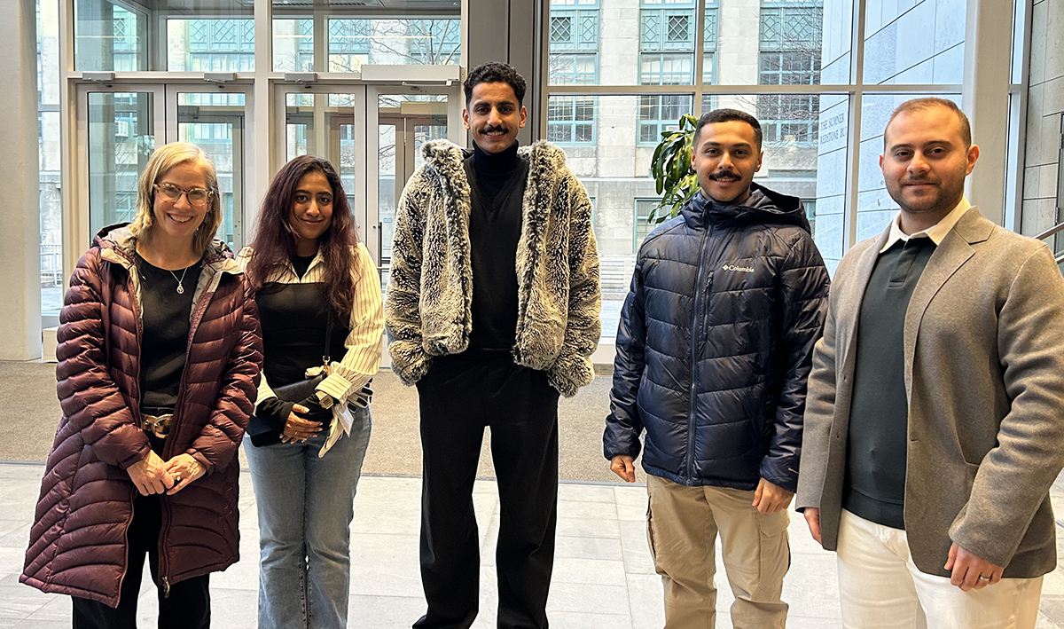 Director Maureen Leo poses for a photo in the atrium with four LLM students.
