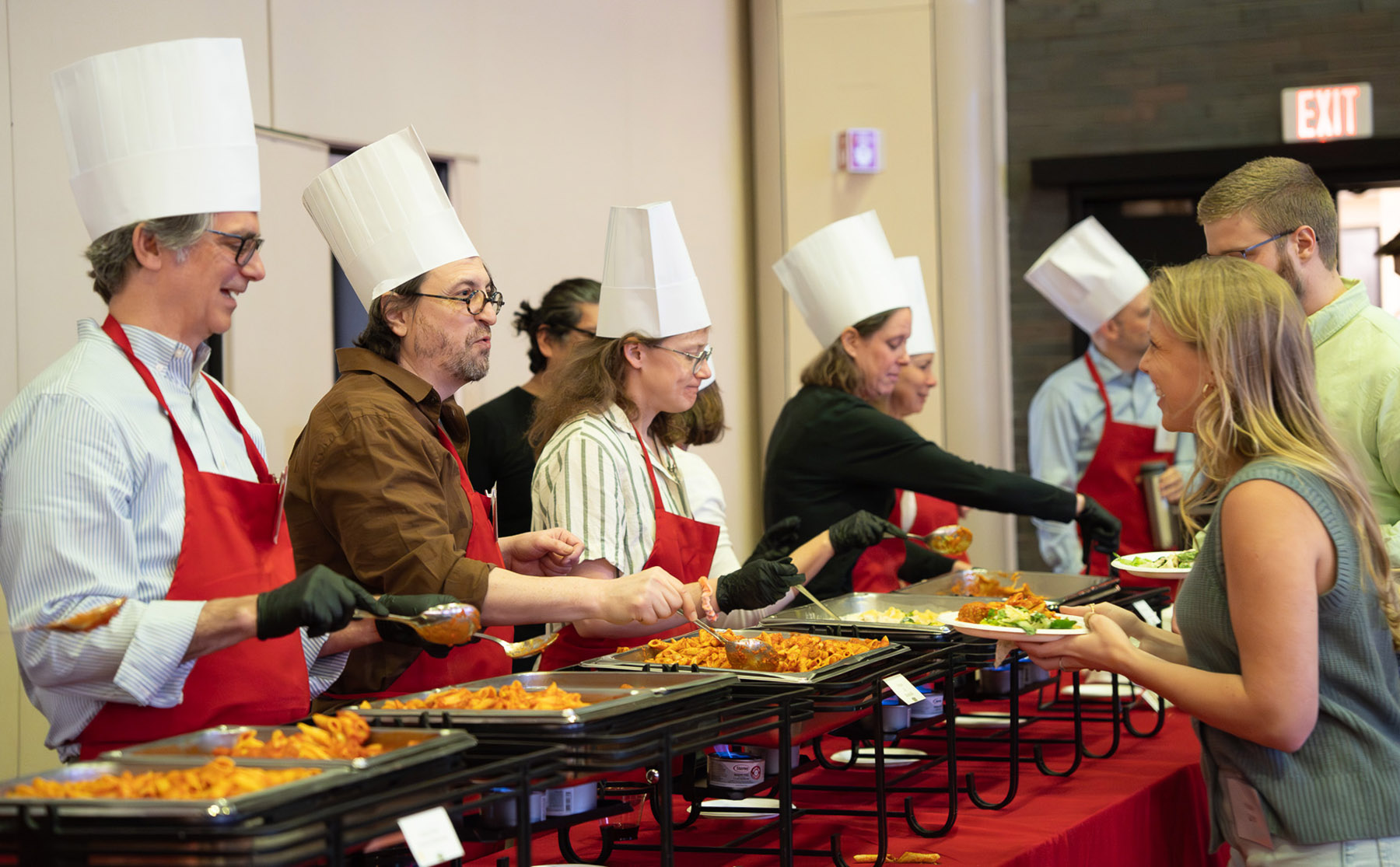 BU Law faculty members wear paper chef's hats and serve a buffet style meal.