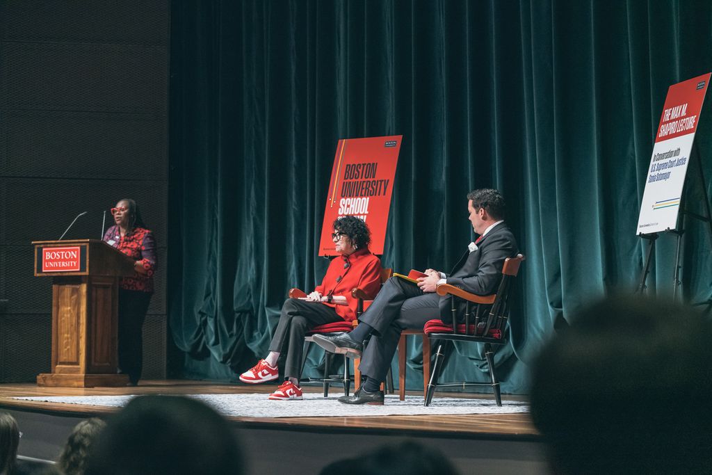 Photo: BU Law Dean Angela Onwuachi-Willig, from left, applauds at a podium while Supreme Court Associate Justice Sonia Sotomayor and Cesar Lopez-Morales sit on stage at the Shapiro Lecture at Tsai Center.
