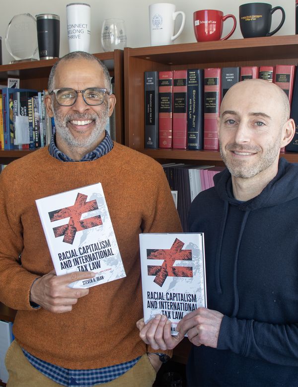 Professor Steven Dean and Professor Jonathan Feingold hold up Steven's book, "Racial Capitalism and International Tax Law"