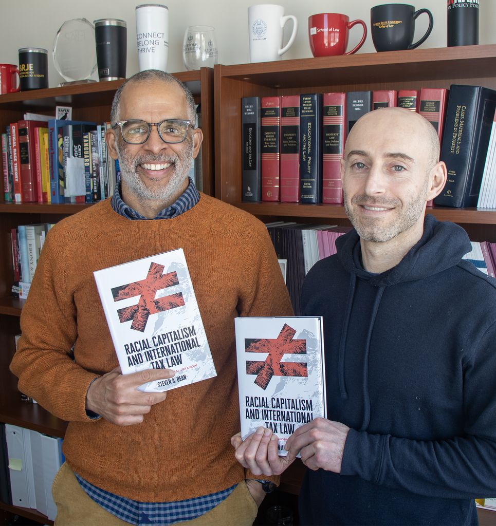 Professor Steven Dean and Professor Jonathan Feingold hold up Steven's book, "Racial Capitalism and International Tax Law"