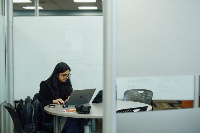 A student working next to a whiteboard in Mugar Library.
