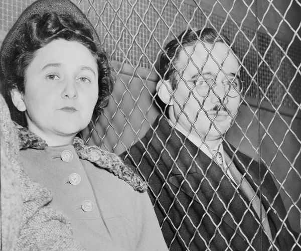 Ethel and Julius Rosenberg sit next to each other with a chain barrier separating them.