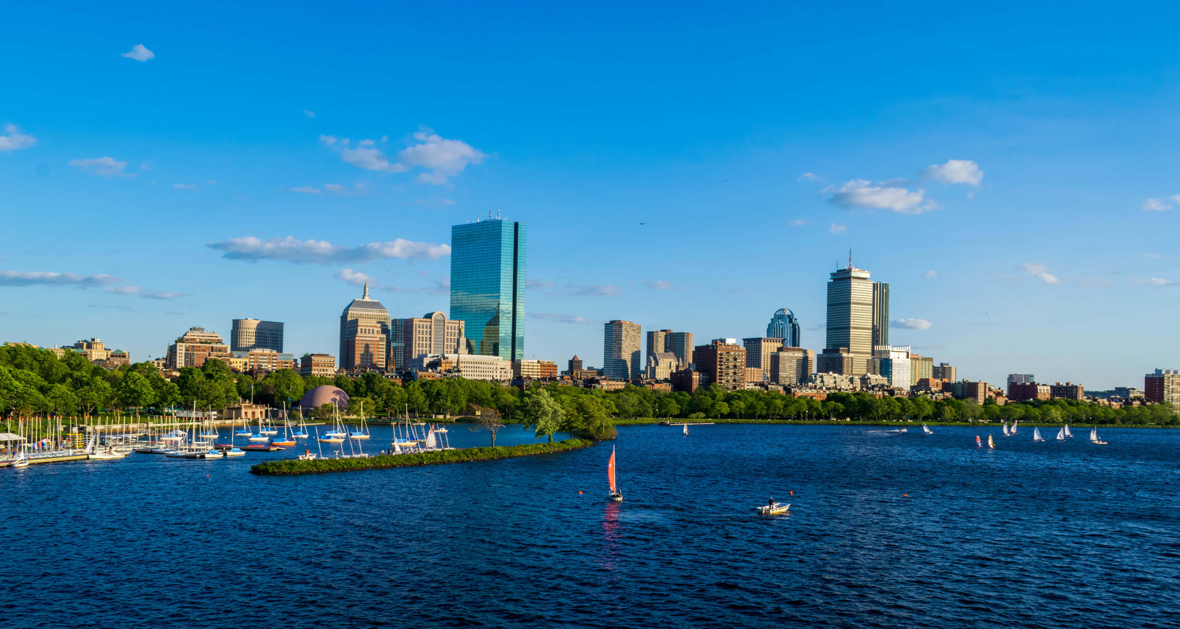 Charles River with the Boston city skyline and blue skies in the background.