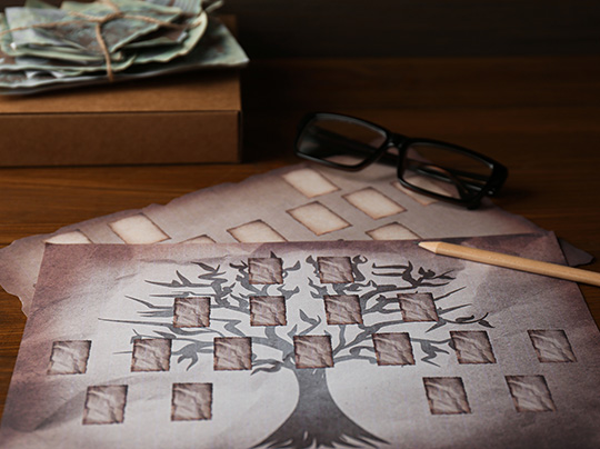 Papers with family tree templates, pencil, photos and glasses on wooden table