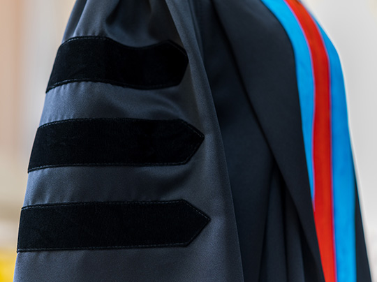 A closeup photo of a graduate wearing PhD regalia