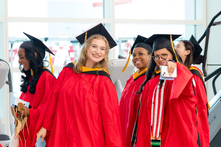 A group of students posing for the camera while walking towards the 2025 MET Convocation ceremony