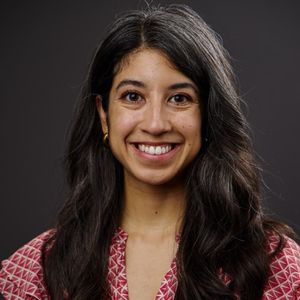 Melissa Paz headshot, smiling in front of black background