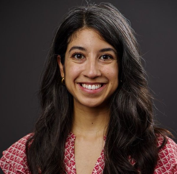 Melissa Paz headshot, smiling in front of black background