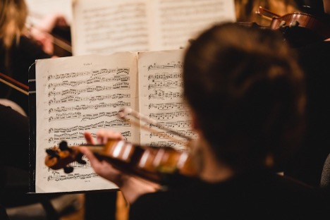 Looking over the shoulder of a violin player, focusing on the sheet music in front of her.