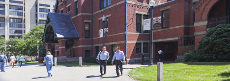 Two individuals walking along a path in front of a brick building