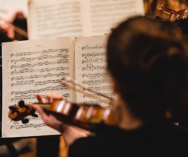 Looking over the shoulder of a woman playing the violin. The sheet music in front of her is in focus.