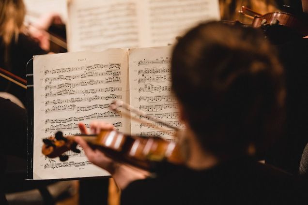 Looking over the shoulder of a woman playing the violin. The sheet music in front of her is in focus.