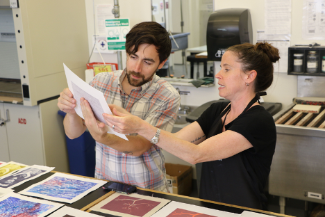 A man and a woman holding and examining a print