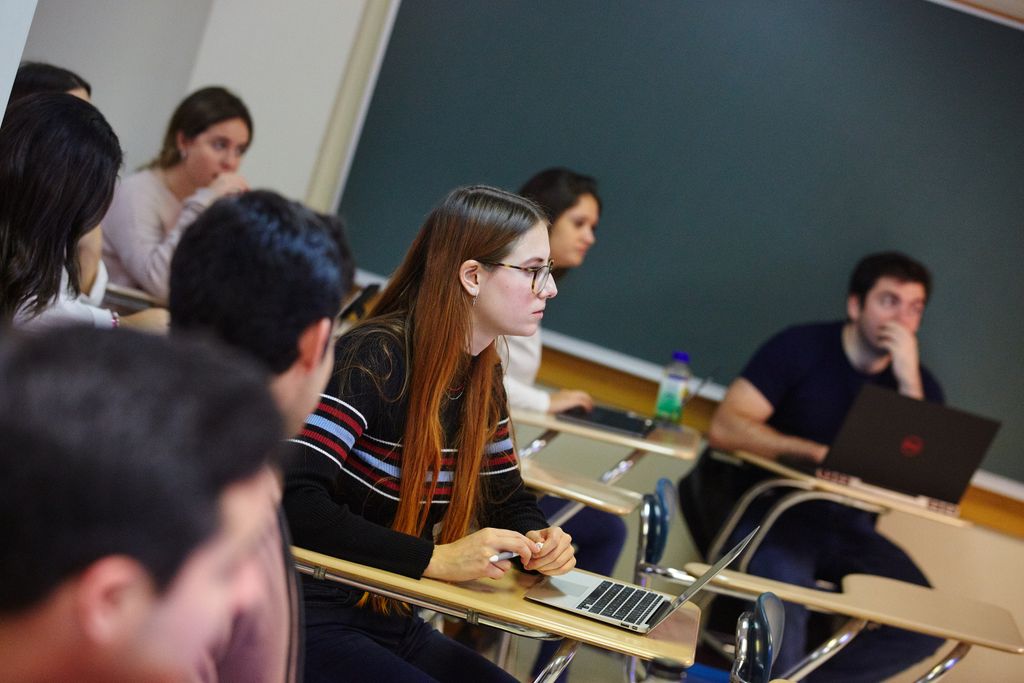 Students at desks attentively looking toward and off-camera professor