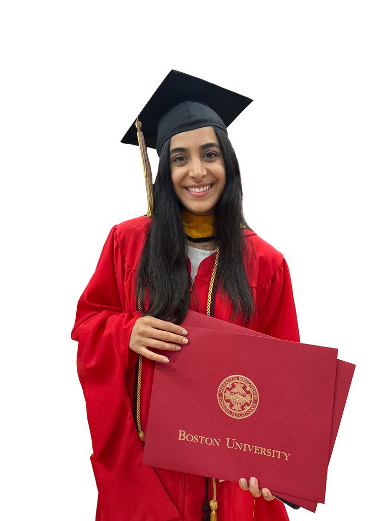 student stands in graduation regalia holding her diploma