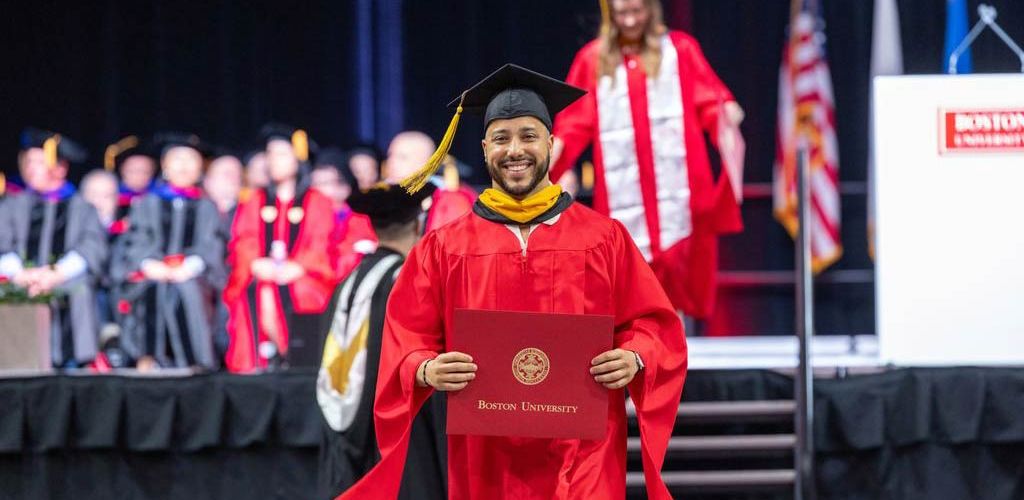 Man walking down the aisle with his diploma