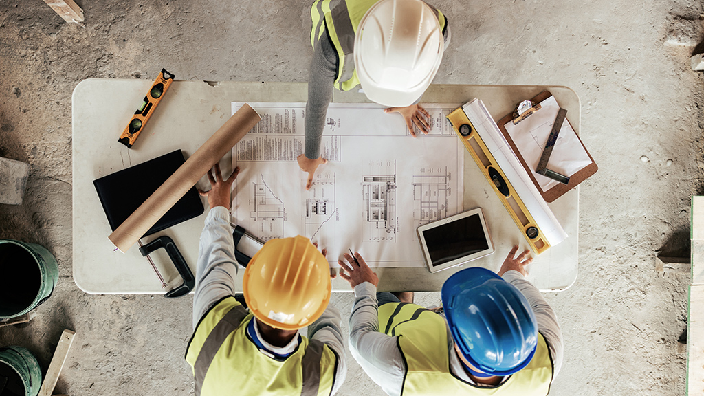 A team of construction workers reviewing blueprints on a construction site
