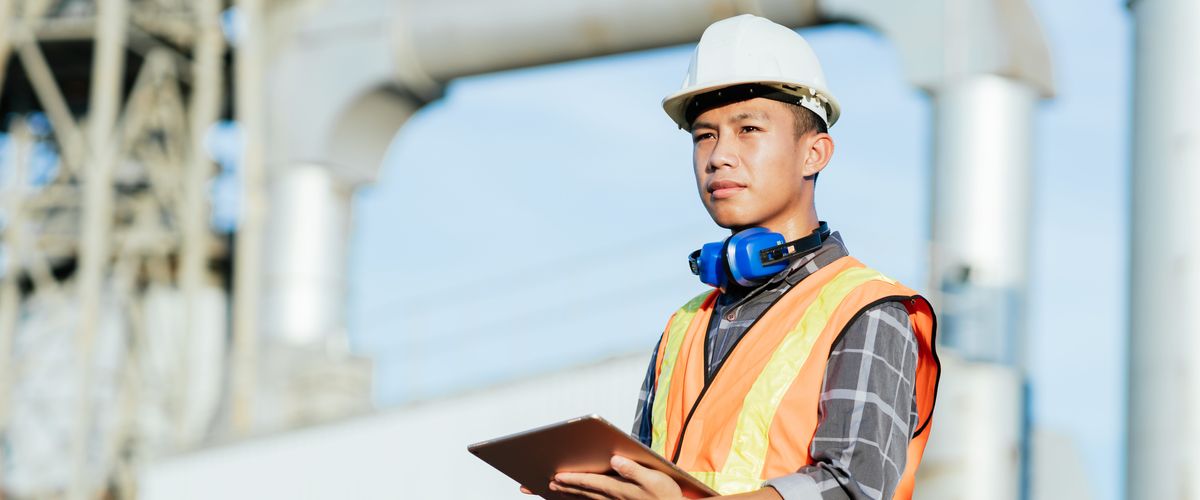A construction worker overseeing progress on-site and taking notes on a tablet