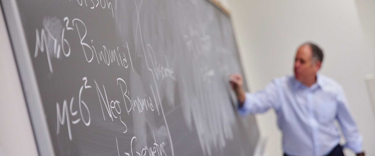 Associate Professor of the Practice Hal Tepfer writes notes on a chalkboard for an Actuarial Science class