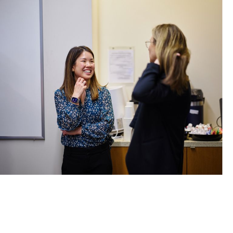 Smiling faculty members chat with each other.