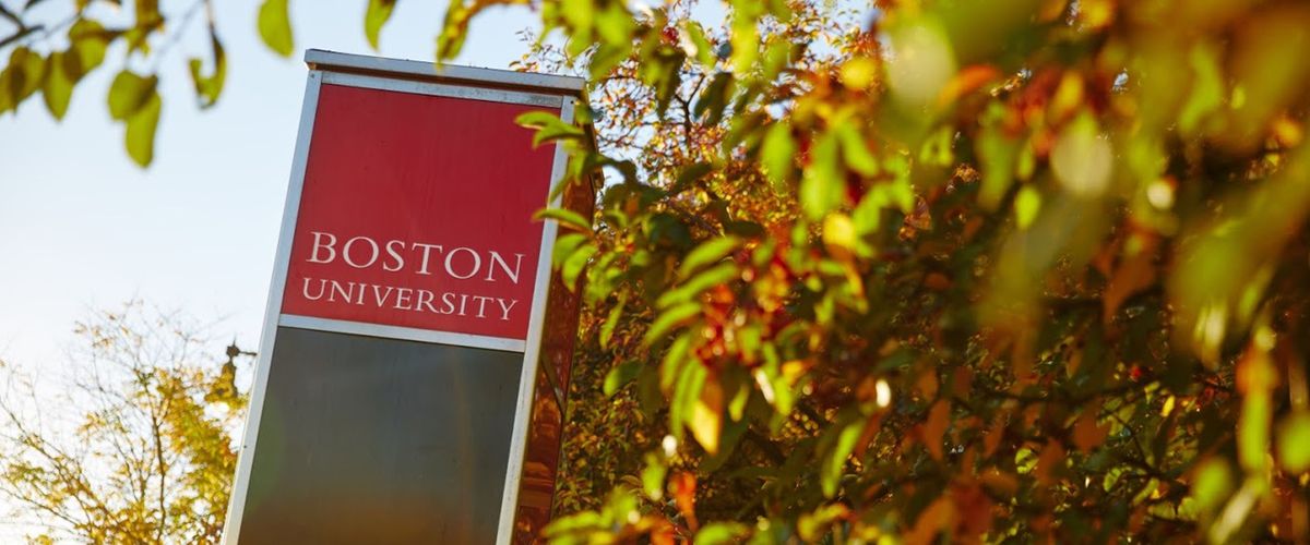 Red Boston University wayfinding sign in amidst leaves