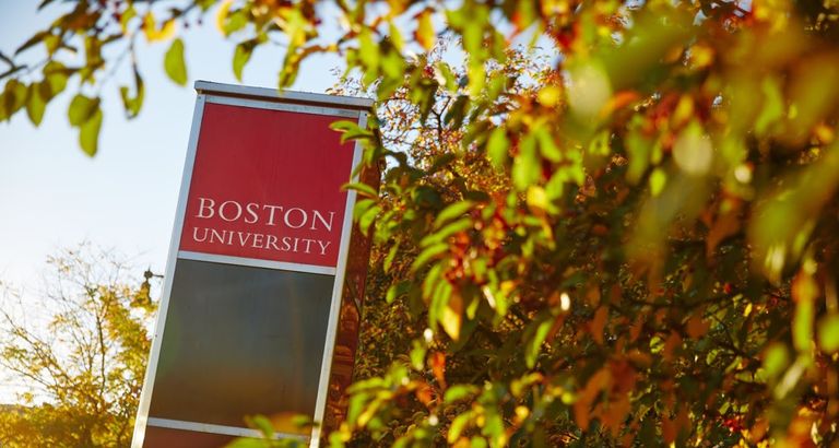 Red Boston University wayfinding sign in amidst leaves